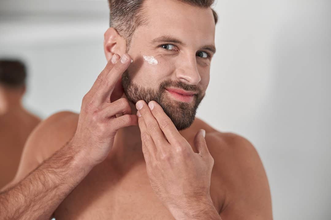 Hombre con barba aplicando crema en la cara