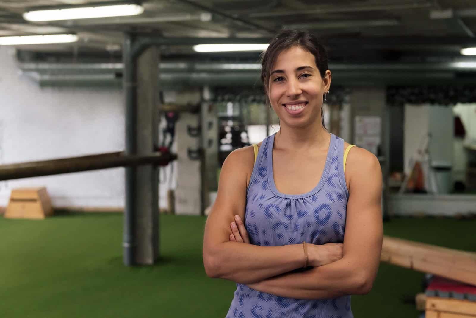 Mujer de brazos cruzados y sonrisa porque es dueña de un gimnasio y de suplementos deportivos