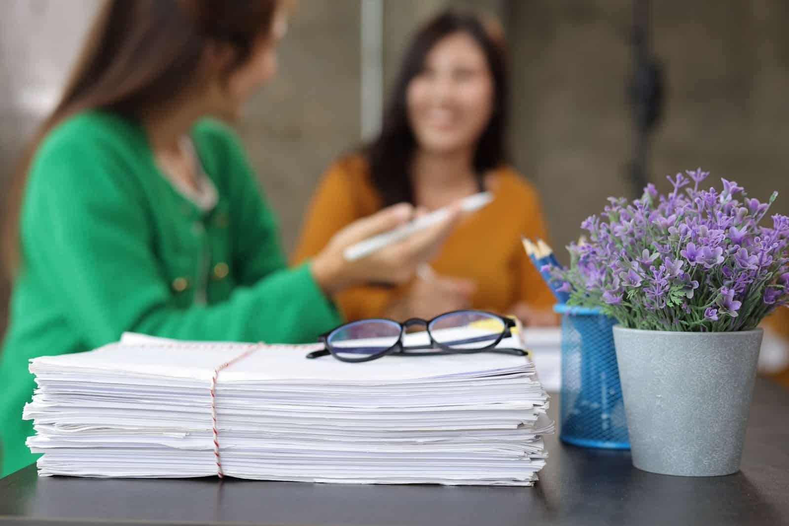 Papeles agrupados con fondo de mujeres platicando sobre estándares de calidad